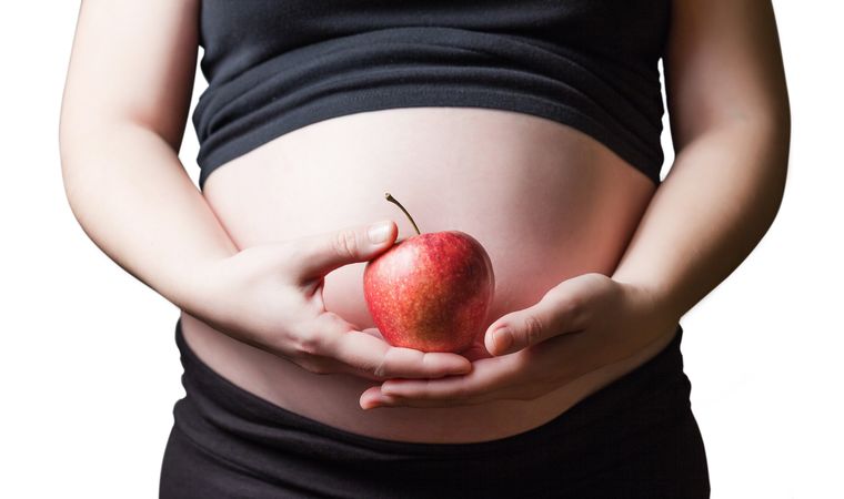 Pregnant woman holding a red apple in her hands