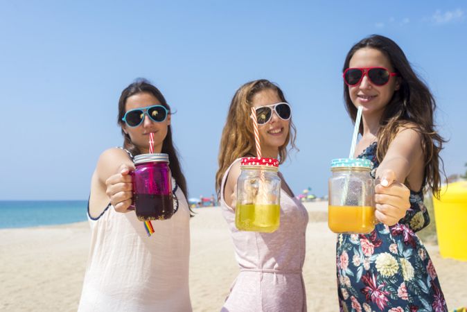 Group of happy teenage friends toasting non alcoholic drinks on summer beach