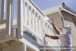 House Painter Spray Painting A Deck of A Home 47m7yO