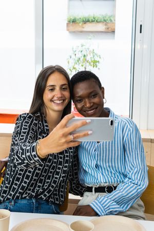 Smiling multiethnic coworkers taking selfie during break in office