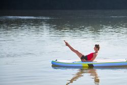 Woman doing ab workout on paddleboard in the sunrise