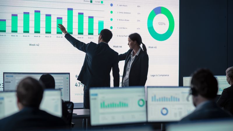 Business Professionals Analyze Data on Large Screen.