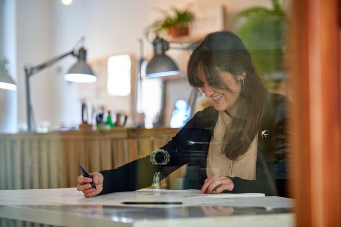 Smiling woman making sketches on papers in studio