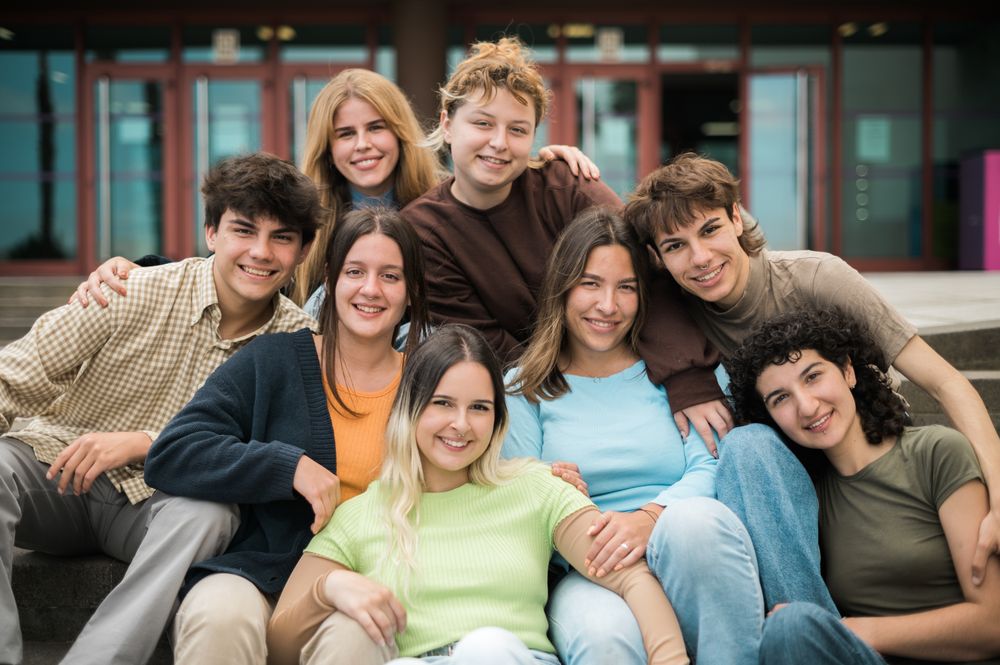 Delighted young friends cuddling and smiling at camera on street