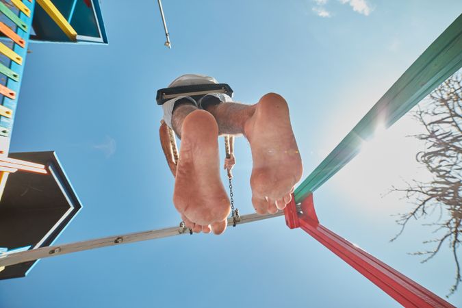 Man swinging on playground in sunlight