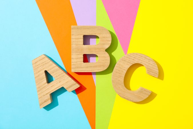 Letters ABC lined with wooden letters on multicolor background
