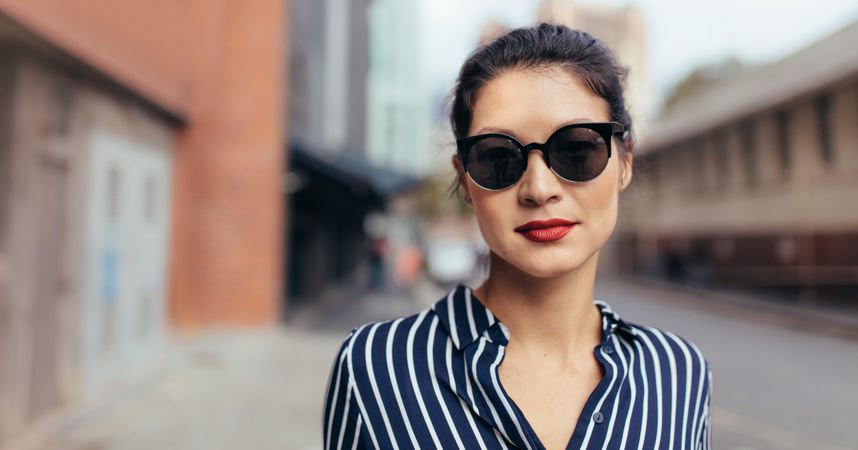Portrait of woman wearing sunglasses walking outside on the city street