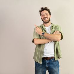 Happy young man pointing to the side at a blank copy space.