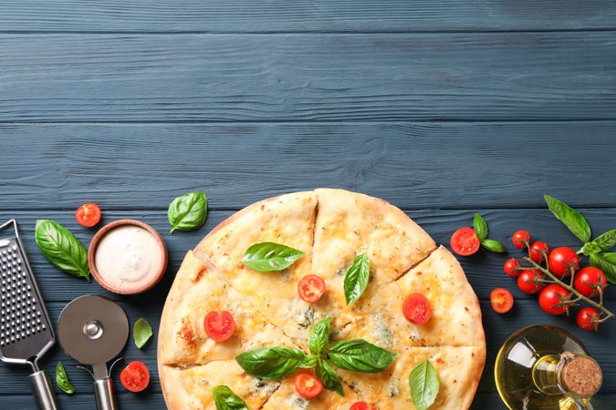 Cheese pizza and ingredients on wooden background, copy space