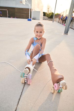 Content girl putting on roller skate in city