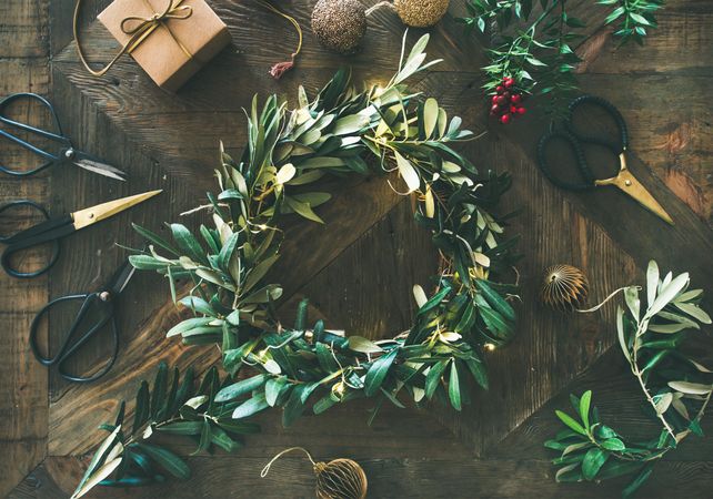 Olive branch festive wreath with scissors and holiday decorations, horizontal composition