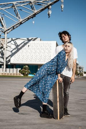 Trendy loving couple on square against modern building and big crane