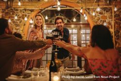 Host couple toasting drinks with guests at dinner party 5oq9kb