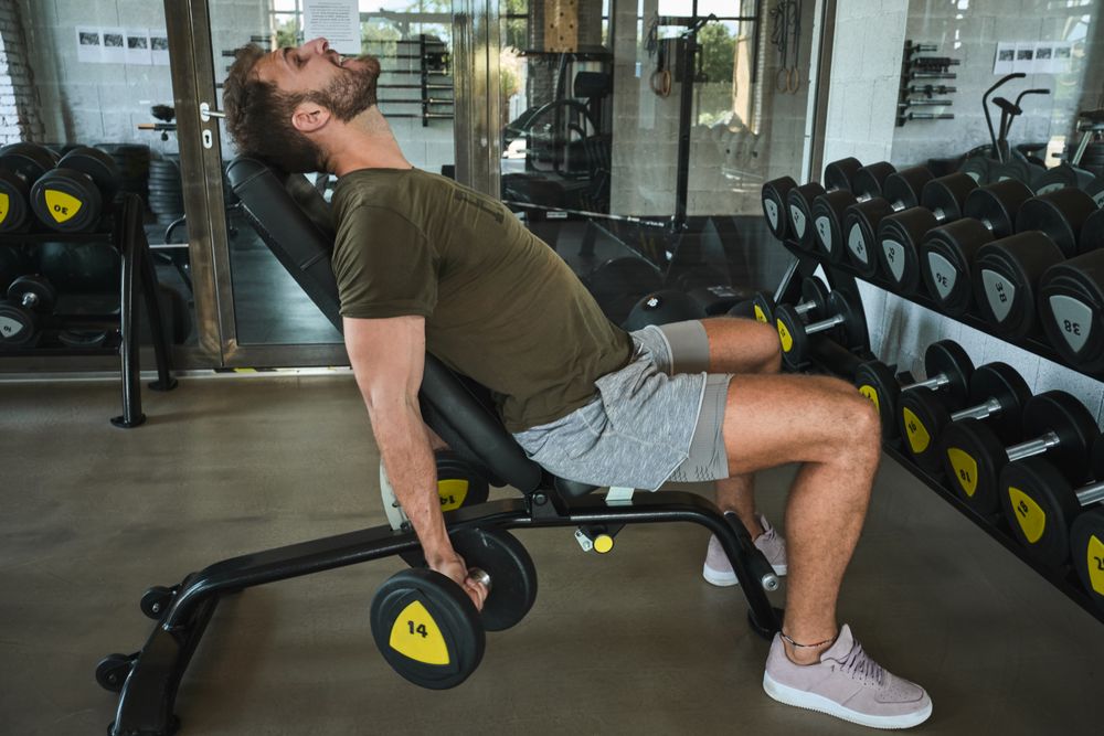 Strong man exercising with dumbbells in gym