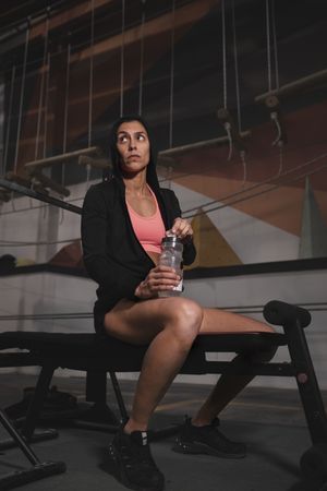 Smiling woman with bottle of water in gym