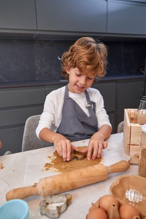 Content boy cutting cookie dough