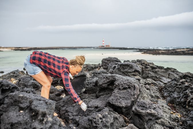 Content modern woman picking litter from sandy seashore