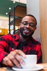 Smiling Black man with cup of coffee in cafe