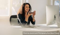Happy woman entrepreneur at her desk in office talking over mobile phone on speaker 4MLka5