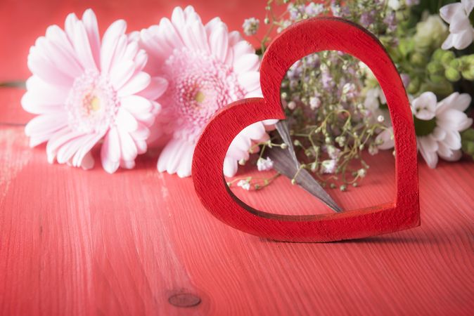 Decorative red heart and chrysanthemum flowers on red rustic table