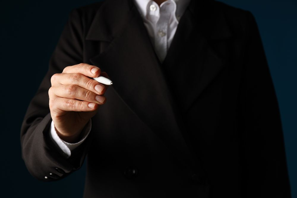 A man in a suit holds a pen