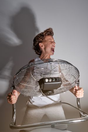 Excited boy screaming in front of blowing fan