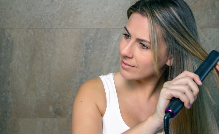 young woman straightening hair with a straightener