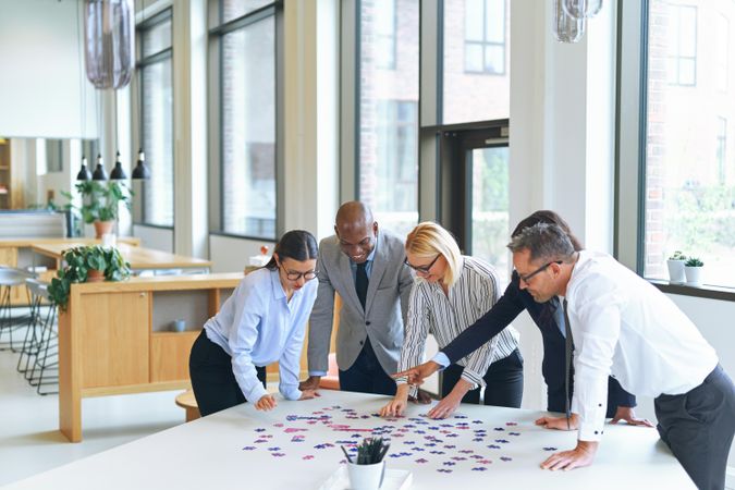 Group of people working together on a puzzle in a modern bright office