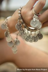 Woman wearing silver coin charm bracelets and ring 0Lpgr0