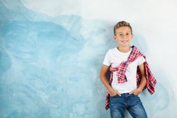 Boy in t-shirt, jeans and shirt against color background, space for text