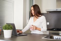 Smiling woman browsing on laptop and sitting on settee