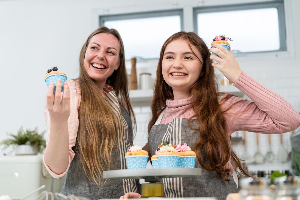 Smiling mother and daughter proud showing homemade cupcakes