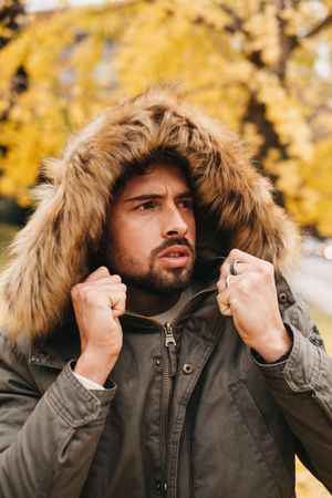 Young male wrapping up in hooded jacket