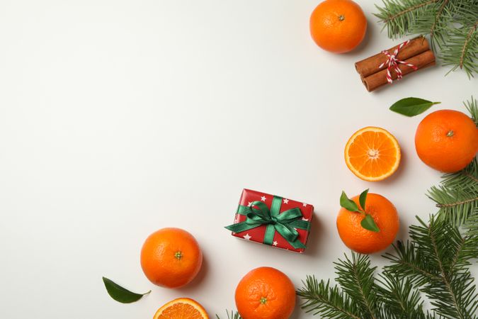 Mandarins, pine branches, cinnamon and gift box on light background
