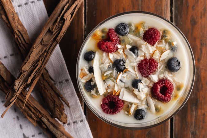 Yogurt in glass bowl with berries and cinnamon sticks
