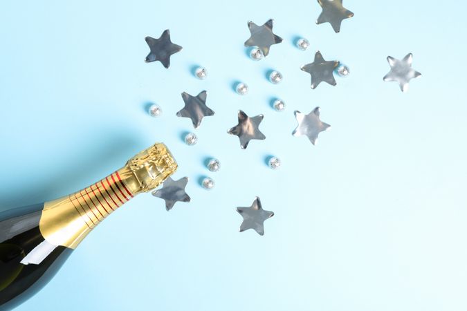 Champagne bottle and glitter on blue background, space for text