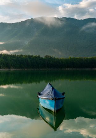 Fishing boat on Lake Sylvenstein and the mountain reflection in the water