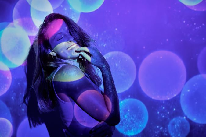 Gleeful female touching chin under colorful sparkles