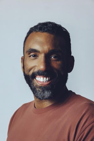 Portrait of smiling Black male in grey studio, vertical