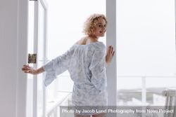 Woman standing near the balcony door in the morning 0Pjk6l