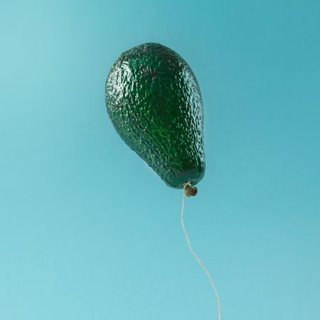Balloon made of avocado fruit on blue background