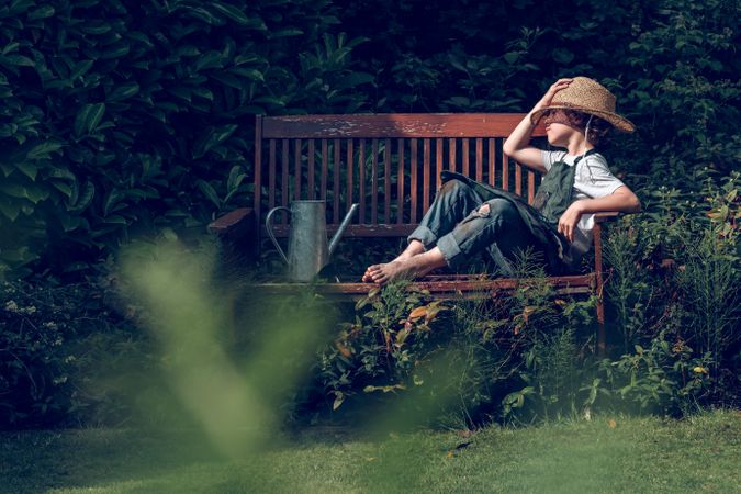 Relaxing kid on bench in garden after work