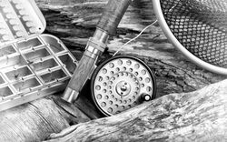 Vintage antique fly fishing outfit  and lures on riverbed setting