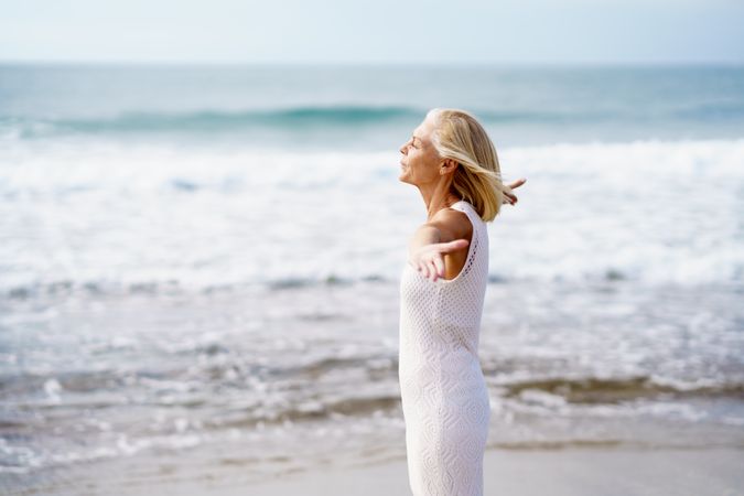 Mature woman with outstretched arms on the coast