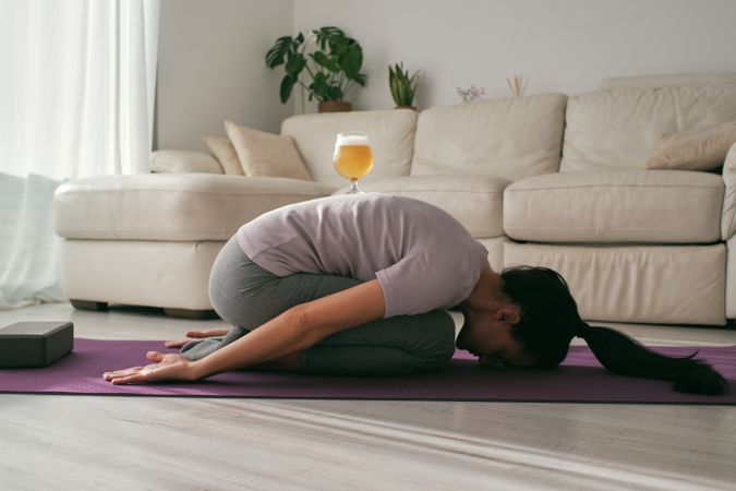 Woman doing Childs asana with beer