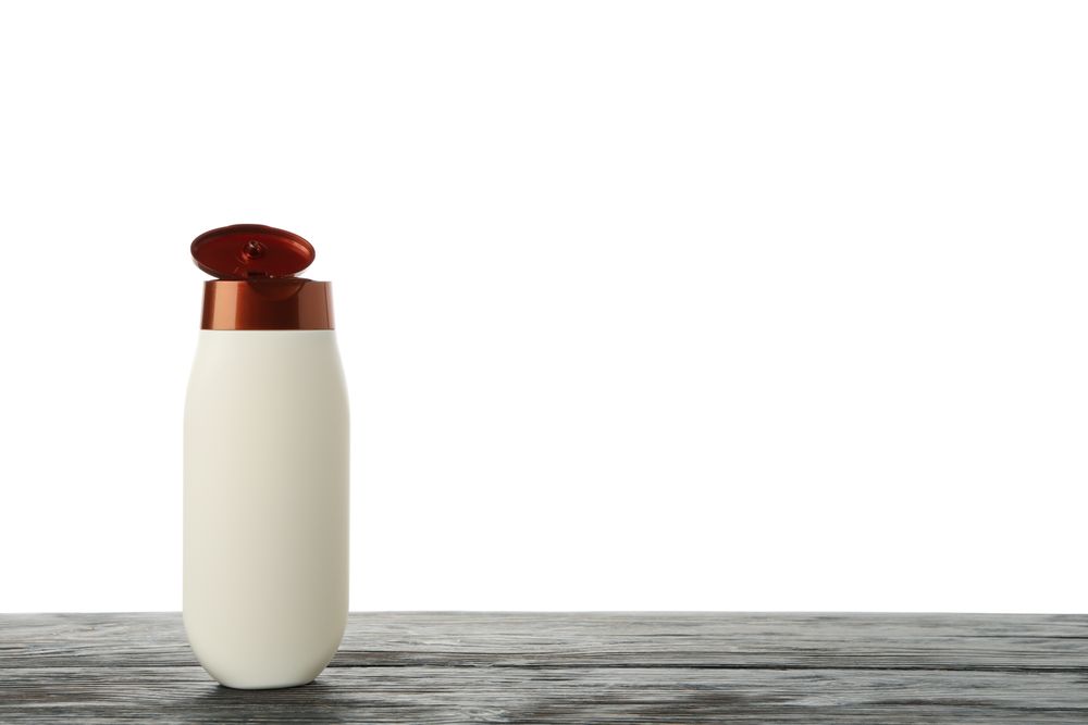 Blank shampoo bottle on wooden table isolated on light background