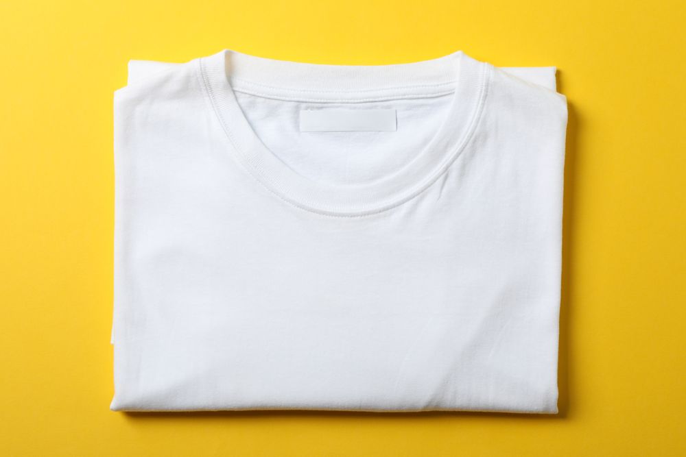 Folded blank plain t-shirt on yellow background, space for text
