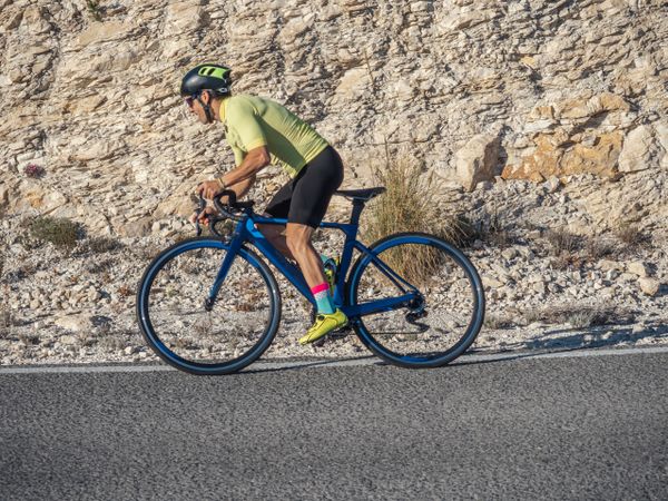 healthy man riding a bicycle on a mountain road in a sunny day