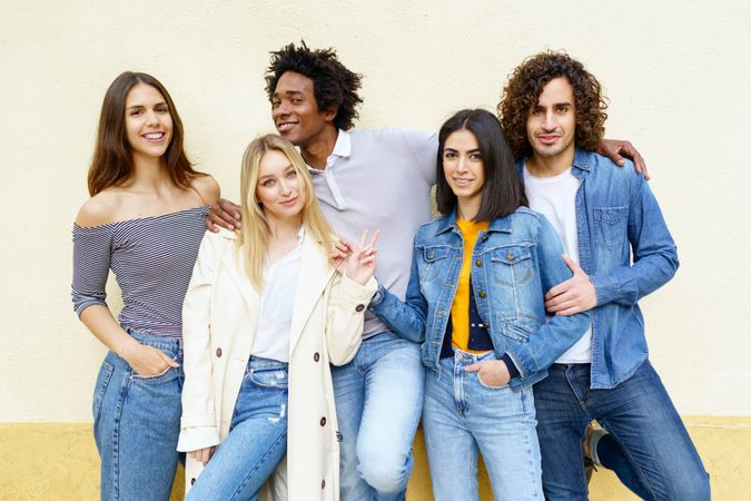 Smiling people posing for portrait leaning against a yellow wall