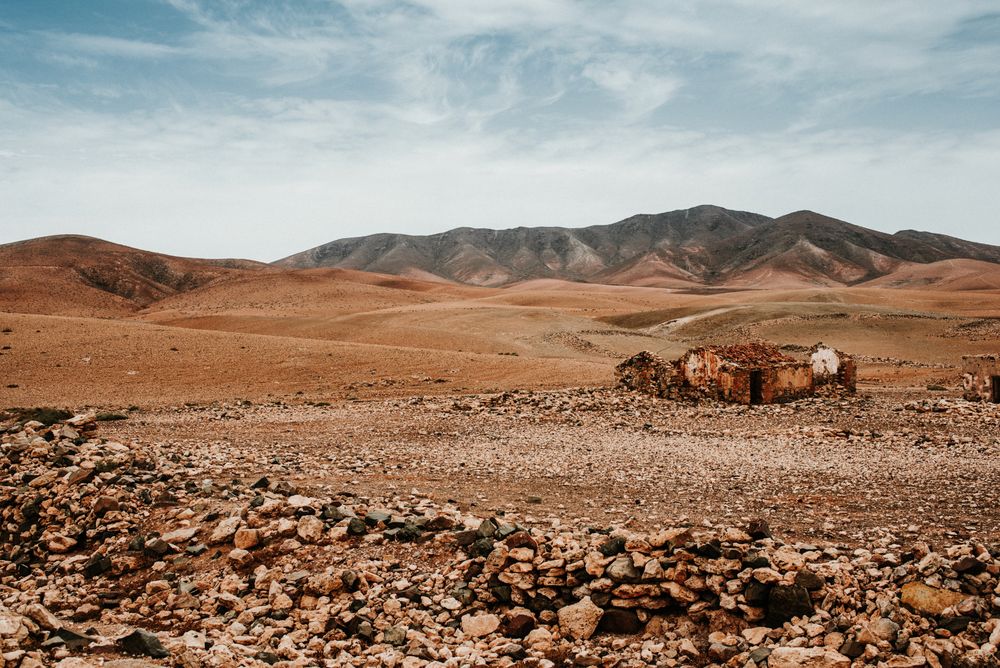 Dilapidated old buildings in mountain desert under cloudy sky